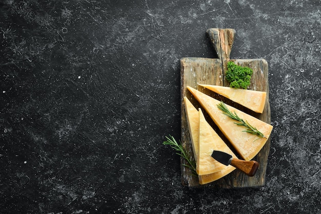 Kawałek parmezanu i nóż do sera Na kamiennym tle Tradycyjny włoski ser Widok z góry Wolne miejsce na tekst