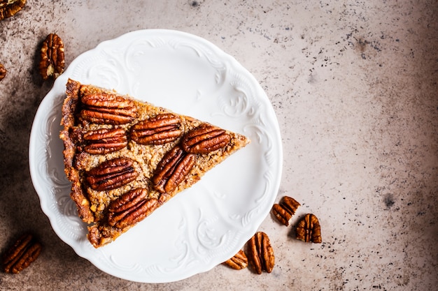 Kawałek pecan Pie na szarobrązowym tle, widok z góry. Koncepcja deserów wegańskich.