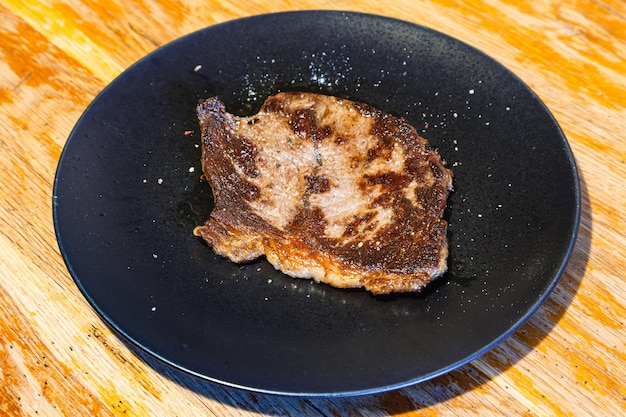 Kawałek pieczonego mięsa na czarnym talerzu na stole