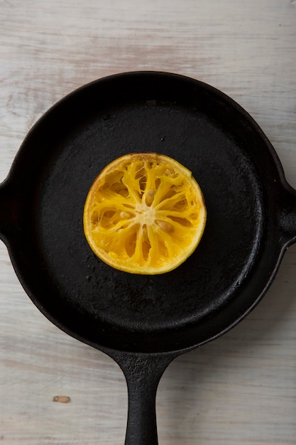 Kawałek pomarańczy surowych owoców na żelaznej patelni na drewnianej podłodze