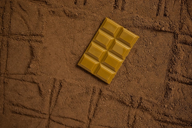 Kawałek tabliczki czekolady na tle tekstury kakao