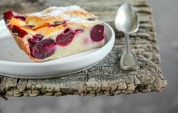 Kawałek tradycyjnego francuskiego deseru domowej roboty ciasto wiśniowe clafoutis w szarym talerzu