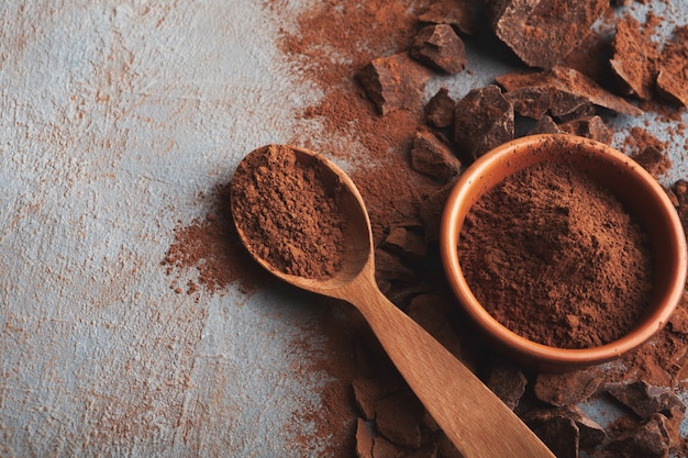 Zdjęcie kawałki ciemnej czekolady zmiażdżony na ciemnym tle i zbliżenie w proszku kakaowym, miejsce. słodka tapeta, reklama sklepu cukierniczego i koncepcja składników do gotowania