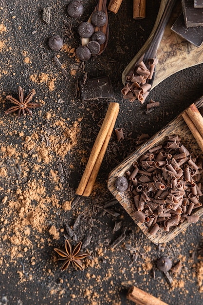 Zdjęcie kawałki czekolady, chipsy i krople z proszkiem kakaowym i przyprawami koncepcja słodkiego jedzenia