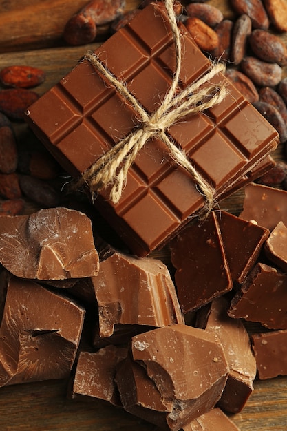Kawałki czekolady, wióry i ziarna kakaowe na kolorowym drewnianym tle