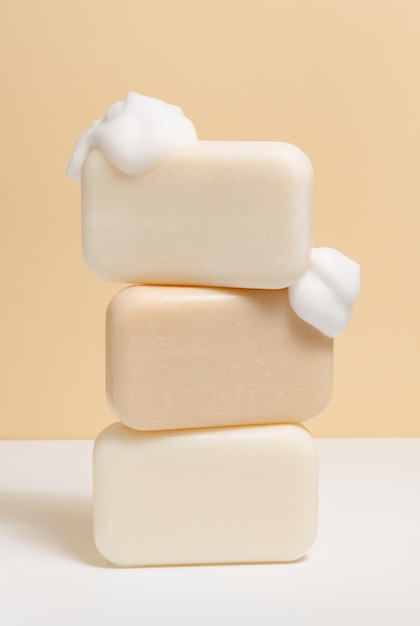 Kawałki naturalnego lekkiego mydła z pianką na beżowym tle pionowego obrazu Koncepcja kosmetyków samoobsługowych