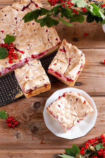 Kawałki słodkiego domowego ciasta porzeczkowego na talerzu z czerwoną porzeczką na drewnianym stole