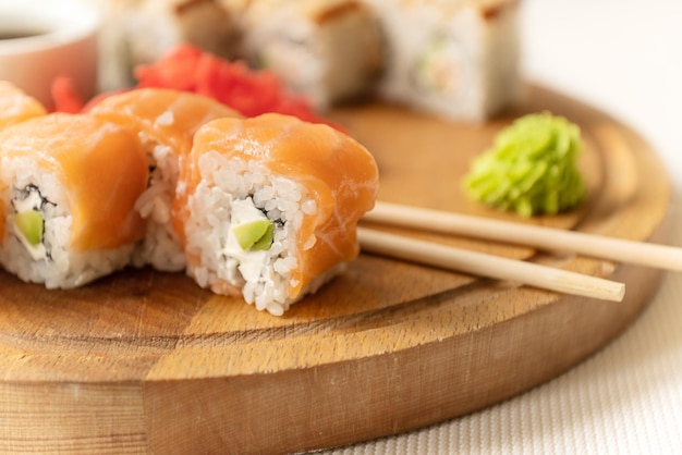 Kawałki sushi z łososiem podawane z wasabi i pałeczkami na drewnianej desce gotowe do spożycia