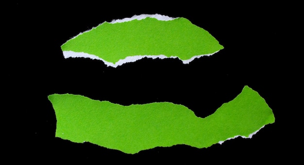 Zdjęcie kawałki zielony rozdarty papier na białym tle na czarnym tle. podarte papiery.