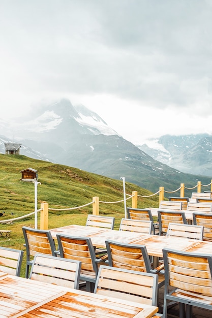 Kawiarnia taras stoły krzesła meble ogrodowe ścieżka gospodarstwa w szwajcarskich górach mglisty krajobraz