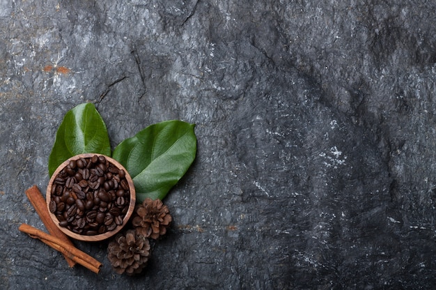 Kawowe fasole w drewnianej filiżance na zielonym liściu, sosna na czerń kamieniu
