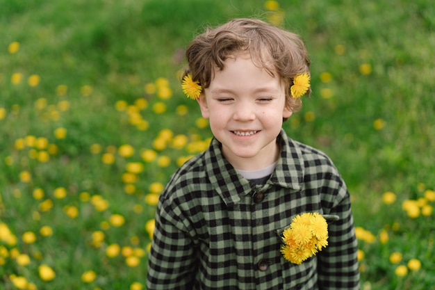Kędzierzawy chłopiec z kwiatami mniszka lekarskiego