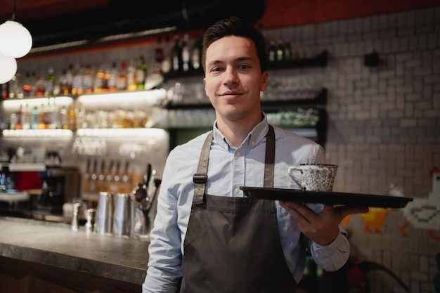Kelner baristy przygotowuje sprzedaż kawy Americano cappuccino z jedzeniem na wynos w kawiarni