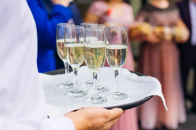 Kelner obsługi cateringowej trzymający tacę z kieliszkami szampana do degustacji