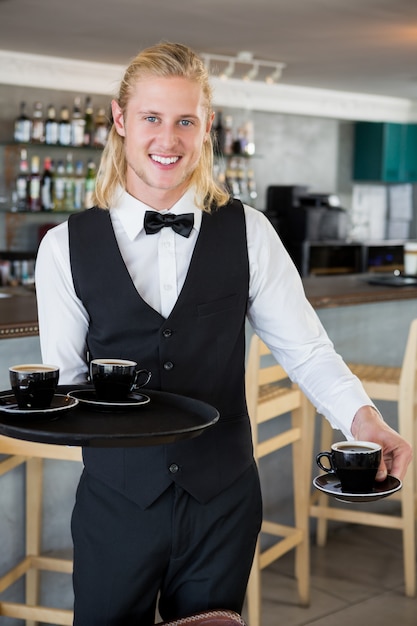 Kelner trzyma tacę z filiżankami kawy w restauracji