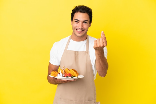 Kelner w restauracji trzymający gofry nad na białym tle żółtym gestem zarabiania pieniędzy