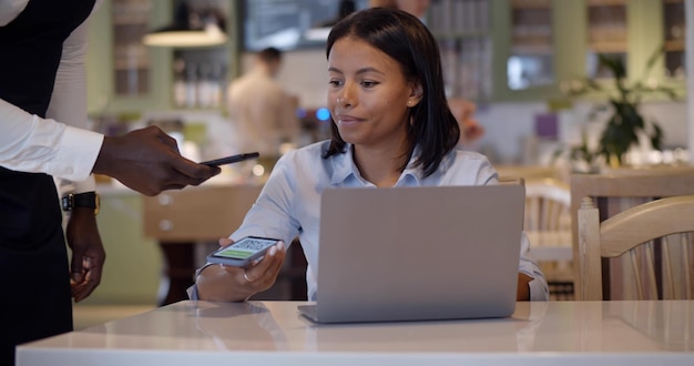 Kelner ze smartfonem skanuje qrcode na ekranie klienta w celu płatności zbliżeniowych