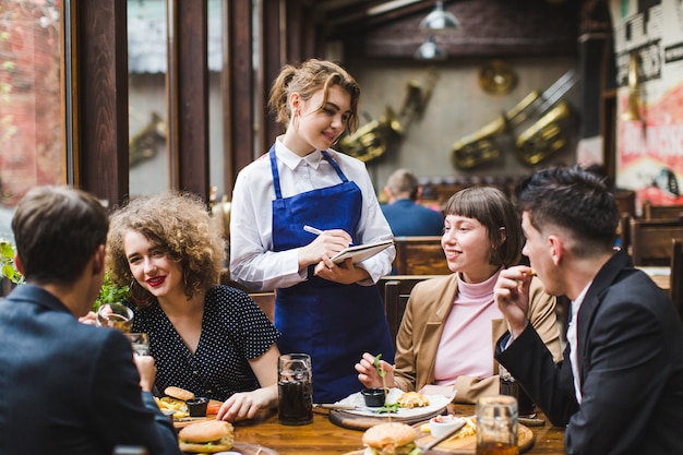 Zdjęcie kelnerka przyjmująca zamówienia od ludzi w restauracji