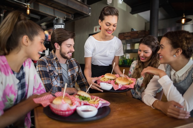 Kelnerka serwująca hamburgery klientom w restauracji