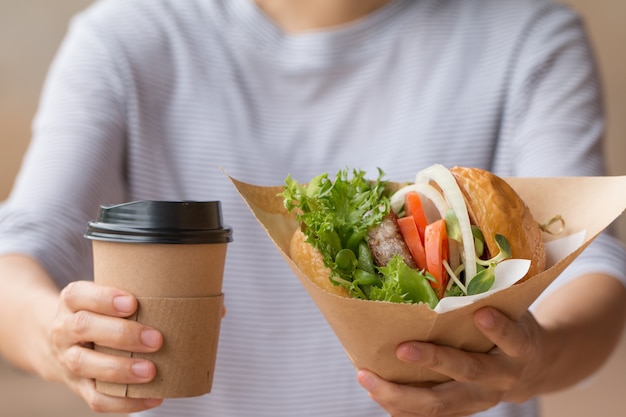 Zdjęcie kelnerka serwuje a burger z kawą dla klienta