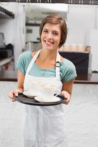 Kelnerka trzyma tacę z cappuccino