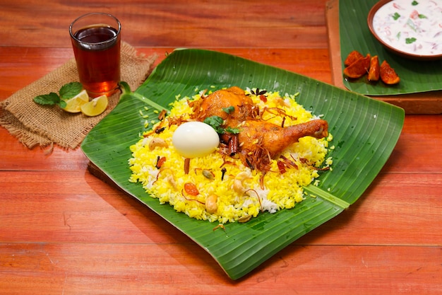 Kerala Kurczak biryani ułożony tradycyjnie w liściu bananowca i raita jako dodatek