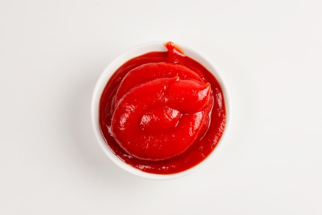 Ketchup w białej płytce na białym tle.