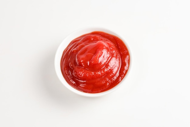 Ketchup w białej płytce na białym tle.