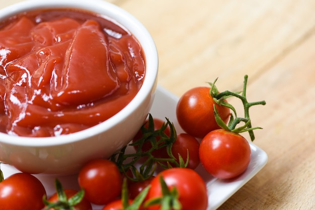 Ketchup w filiżance i świeżych pomidorach na talerzu