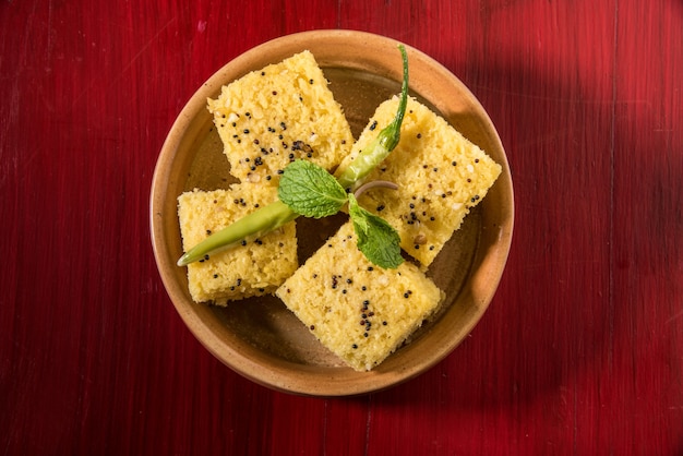 Zdjęcie khaman dhokla to wegetariańska przekąska lub produkt śniadaniowy z indyjskiego stanu gujarat. podawane ze smażonym zielonym chilli