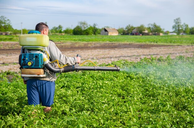 Kherson oblast Ukraina 22 maja 2021 Farmer rozpyla plantację ziemniaków rozpylaczem rozpylacz mgły fungicyd i pestycyd Ochrona roślin uprawnych przed owadami i grzybami