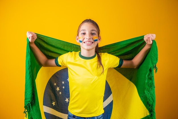 Kibic piłki nożnej, drużyna Brazylii. Piękna mała dziewczynka kibicuje swojej drużynie na żółtym tle