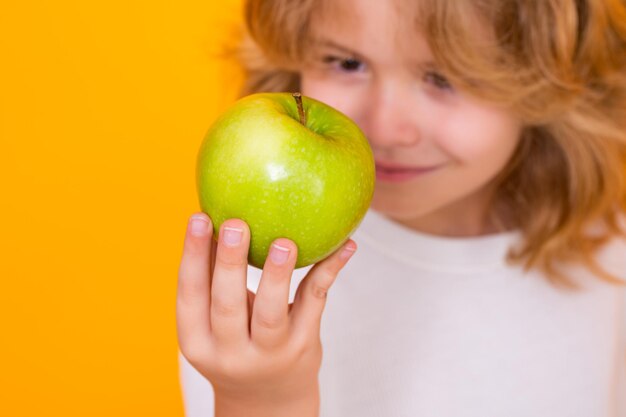 Kid z jabłkiem w studio Portret studyjny cute dziecka przytrzymaj jabłko samodzielnie na żółtym tle