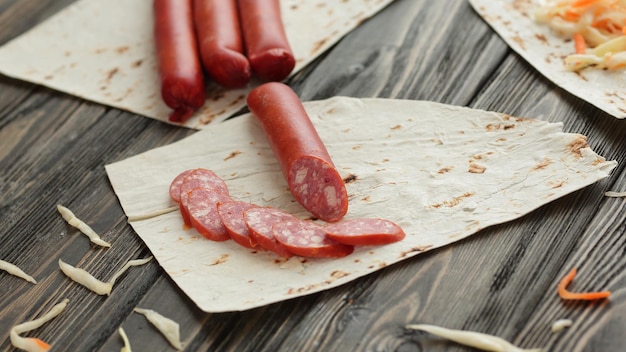 Kiełbasa pokrojona w plasterki do przygotowania kanapki Shawarma na drewnianym backgrou