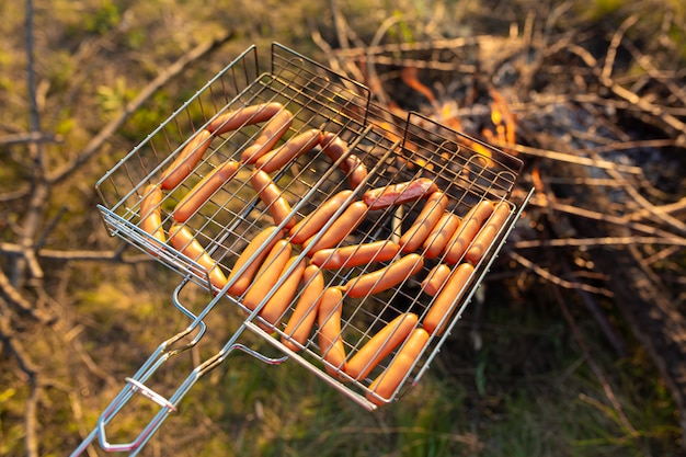 Zdjęcie kiełbaski z grilla na stosie. piknik w naturze o zachodzie słońca. smak lata