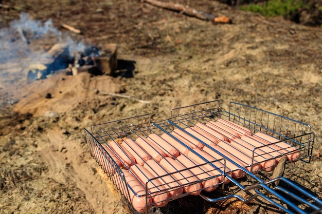 Kiełbasy w grillu przy ognisku gotowe do grillowania