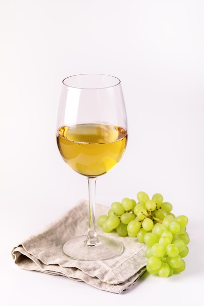 Kieliszek białego wina i gałązka zielonych winogron na białym tle