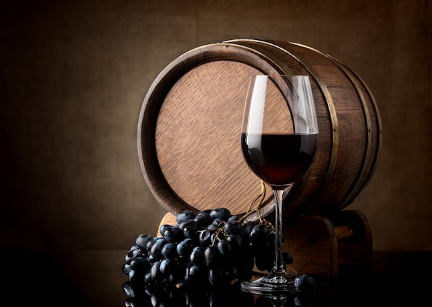 Kieliszek czerwonego wina i drewniana beczka