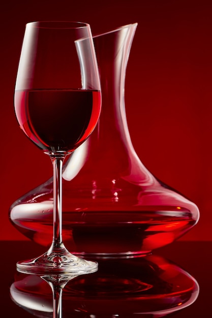 Zdjęcie kieliszek czerwonego wina i karafka na błyszczącym stole.