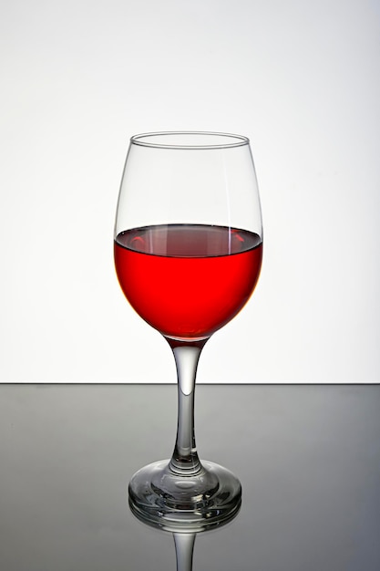 Kieliszek czerwonego wina na odblaskowej powierzchni na białym tle