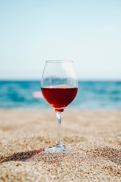 Kieliszek czerwonego wina na tle śródziemnomorskiej plaży i morza w turystycznej miejscowości w...