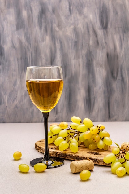 Kieliszek do wina, świeże winogrona i korki na drewnianej desce do krojenia. Winiarnia, winiarnia, koncepcja degustacji wina.