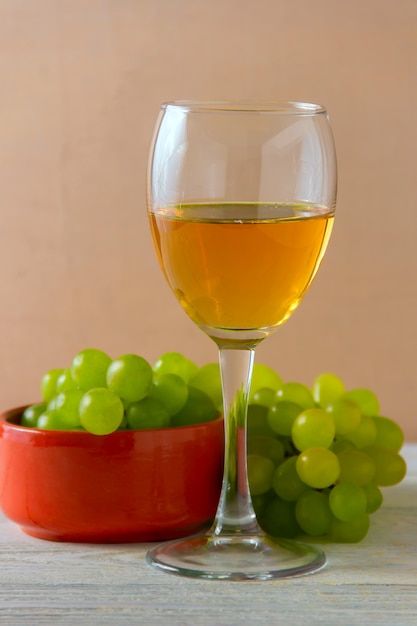 Kieliszek do wina, zielone winogrona na talerzu na stole.