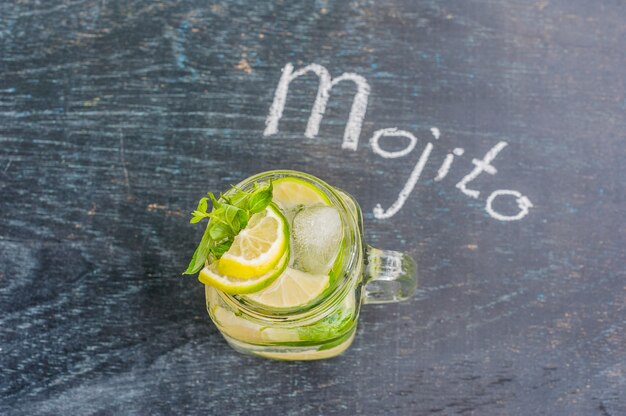 Kieliszek mojito z bliska kostka lodu limonki i mięty na powierzchni ciemnego drewna