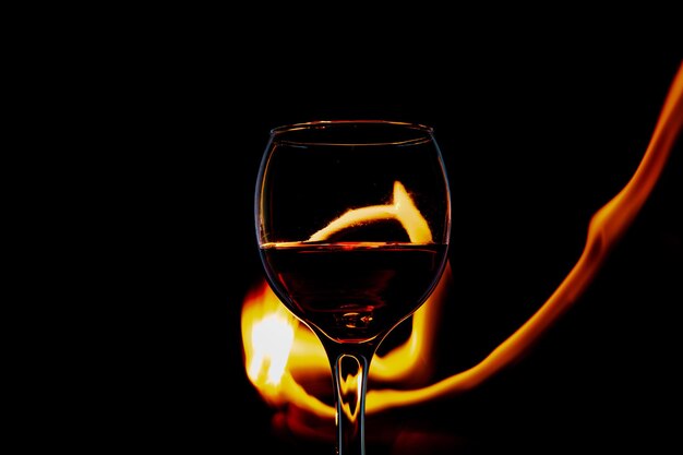 Kieliszek z winem na ogniu i płomieniu na czarnym tle izolacji