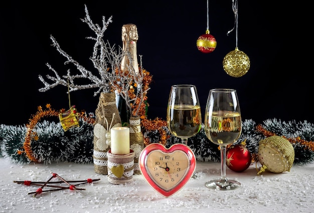 Zdjęcie kieliszki do wina świąteczne zabawki rozgałęziają się świeca i zegar zbliżenie
