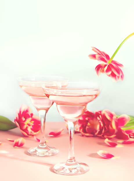 Kieliszki różowych koktajli z kwiatami i płatkami urodziny lub walentynki romantyczna para ko...