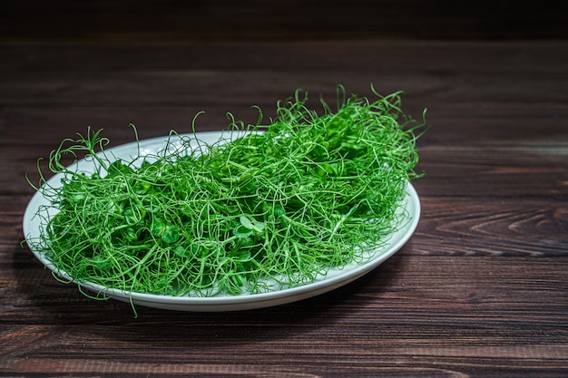 Zdjęcie kiełki microgreen świeże posiekane grochu na talerzu na powierzchni drewnianych