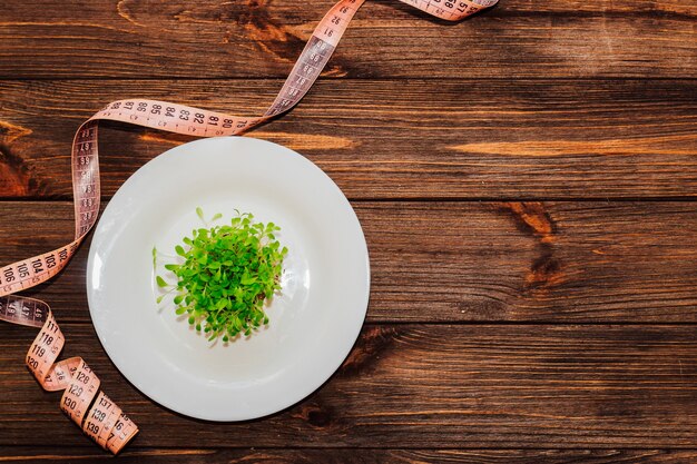 Kiełkujące zielone liście sałaty microgreen w okrągłej białej masce z centymetrem.