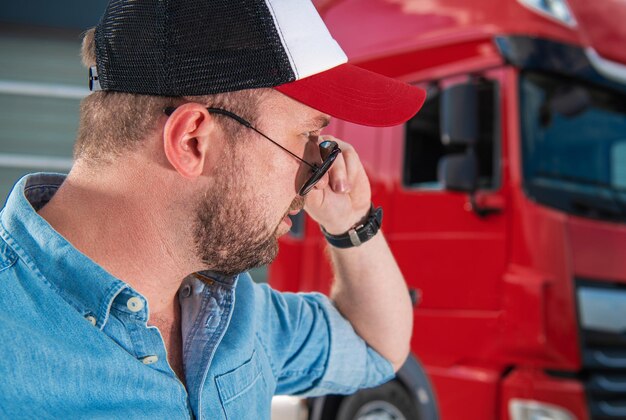 Zdjęcie kierowca ciężarówki w wieku ponad 30 lat patrzy prosto przez okulary przeciwsłoneczne
